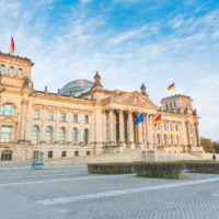 German Reichstag, the parliament building in Berlin German Reichstag, the German parliament building in Berlin at sunset. Some german flags and one European waving. Politics and architecture concepts.